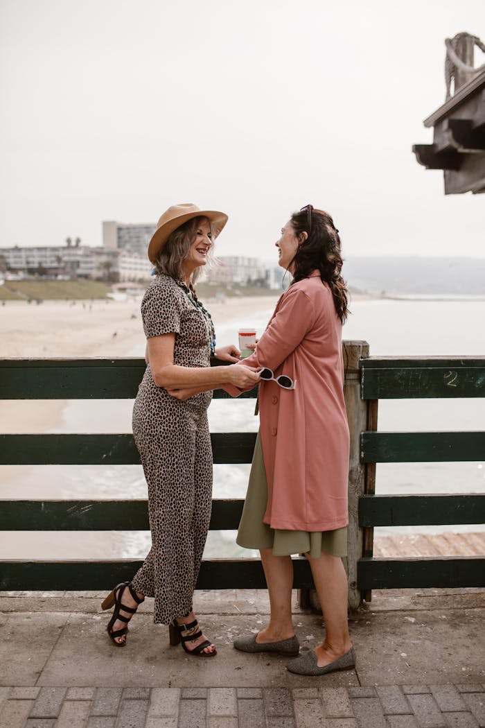 extra-programs-img Two women sharing laughter and holding hands by the beach, embracing friendship and joy.