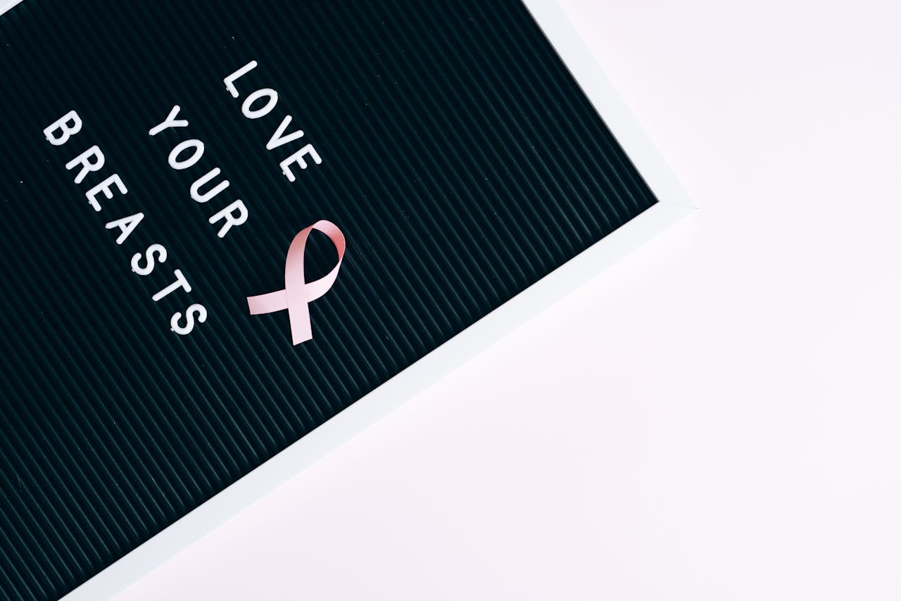 our-history-img Inspirational letter board with pink ribbon promoting breast cancer awareness and self-love.